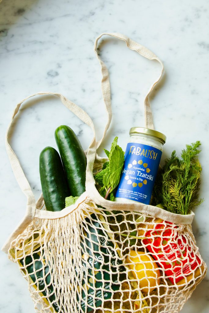 Woven linen bag laying on a counter filled with groceries and produce bought on a budget.