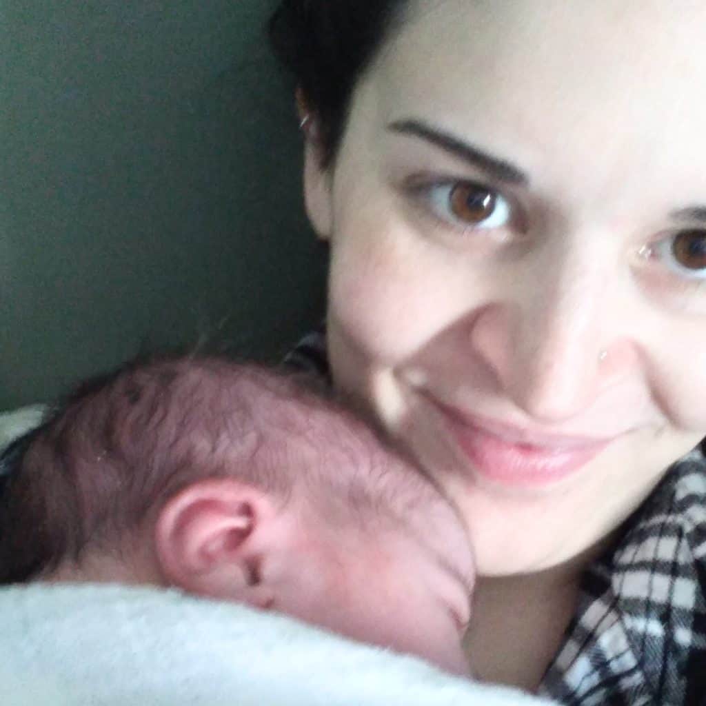 Close up of woman smiling, holding a newborn.