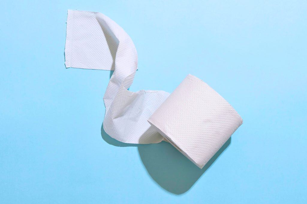Roll of toilet paper against a blue backdrop.
