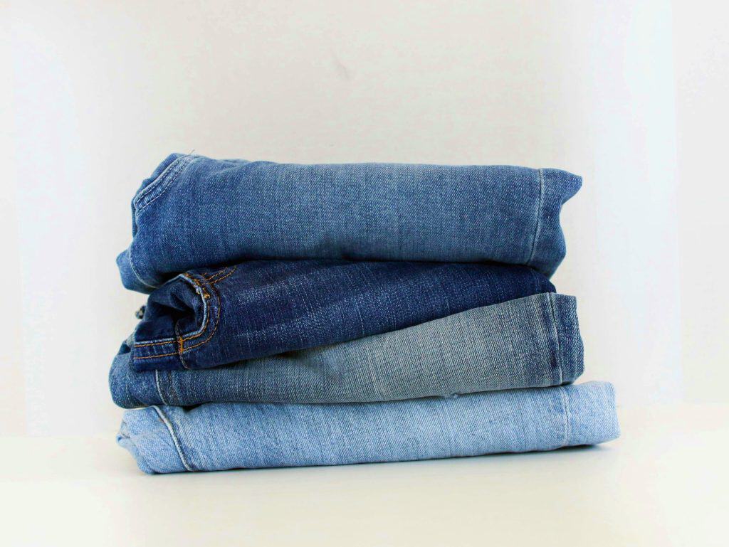 Small stack of assorted blue colored denim jeans.