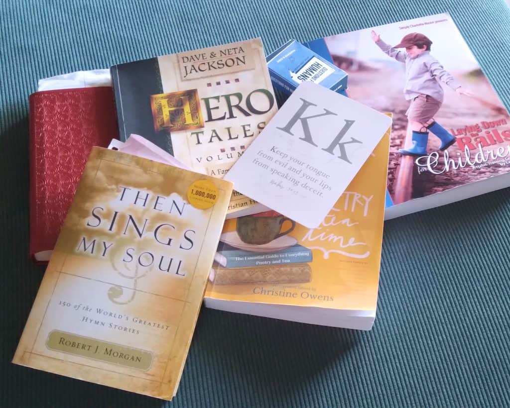 Various books scattered on a blueish green couch.