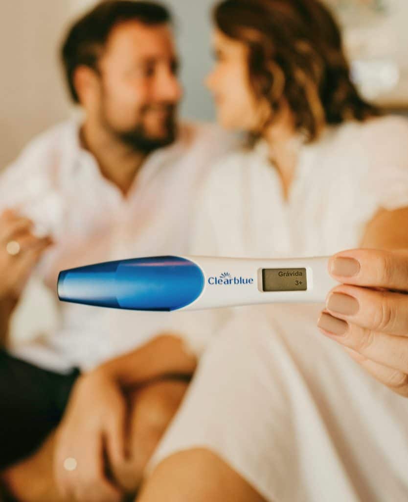 Couple gazing at each other while holding a pregnancy test that reads pregnant.