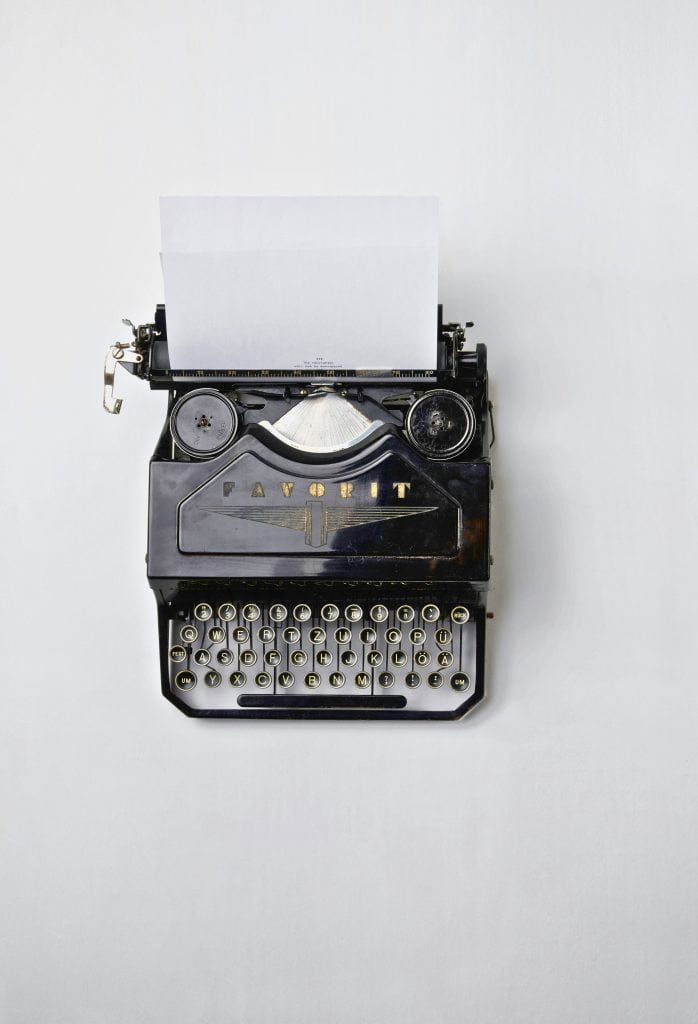 Old school black Favorit typewriter with clean white sheet of paper in place.