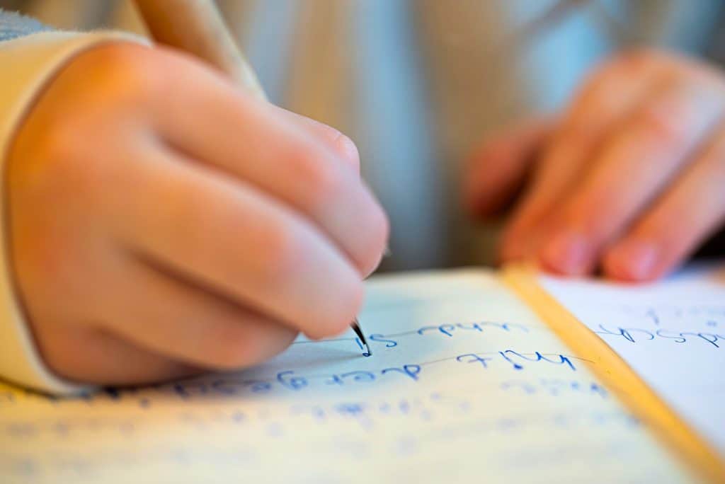 Child holding a pencil and working on basic handwriting.